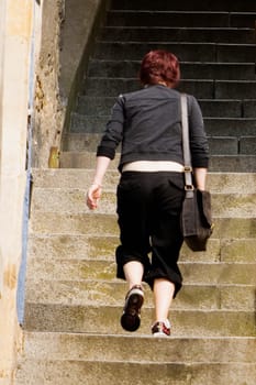 Rear view of a woman climbing up a staircase