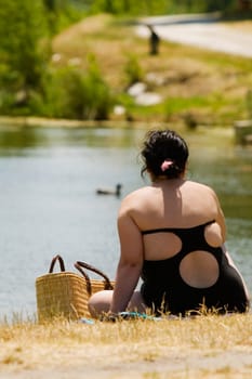Rear view of a woman sitting near a pond