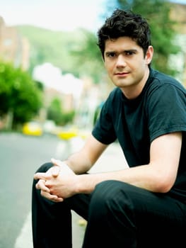 Portrait of a young man sitting with his hands clasped