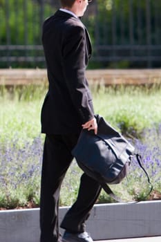 Side profile of a businessman holding a bag and walking