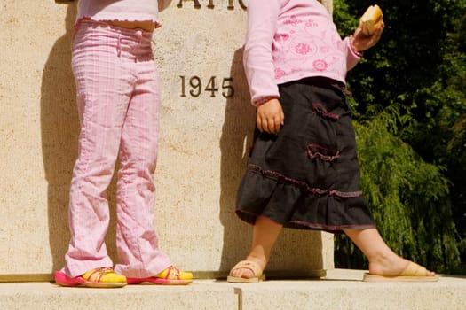 Low section view of two girls standing in front of a war memorial