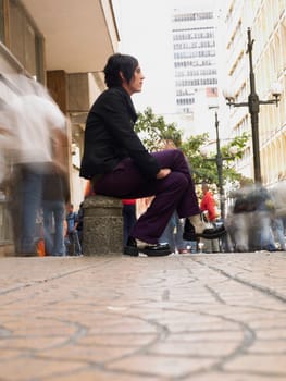 Side profile of a young man sitting at a walkway
