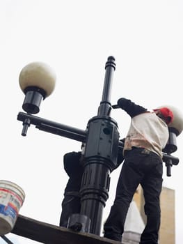 Low angle view of two men painting a lamppost