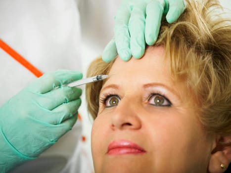 Close-up of a mature woman getting a botox injection on her face