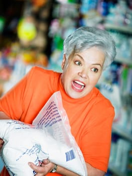 Close-up of a senior woman holding a packet of flour