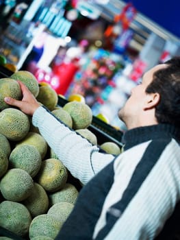 Side profile of a mid adult man taking a cantaloupe