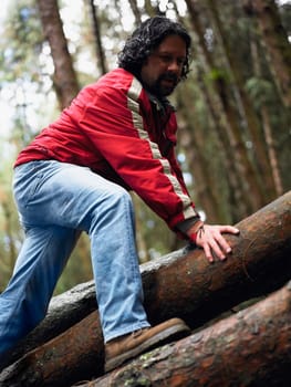 Low angle view of a mid adult man walking on tree trunks