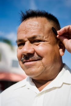Portrait of a mature man holding a pen behind his ear and smiling