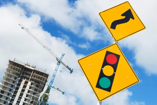Low angle view of a double bend sign with a spotlight sign with a construction site in the background