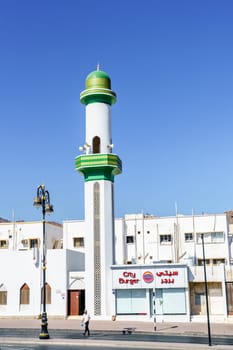 Muscat, Oman, December 3, 2016: A small mosque in Muscat, Oman next to a fast food restaurant