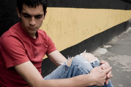 Close-up of a young man sitting against a wall