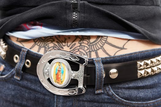 Mid section view of a woman with a belt and a tattoo on her stomach