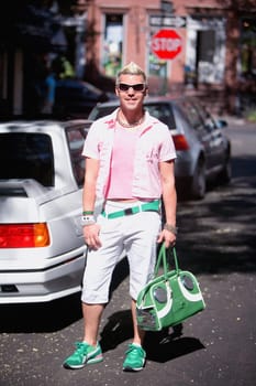 Mid adult man carrying a stereo and standing near a car