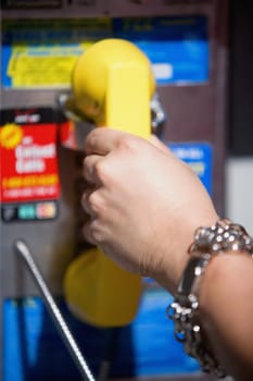 Close-up of a person's hand holding a telephone receiver on a pay phone