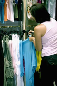 Rear view of a mid adult woman selecting clothes in a clothing store, Barcelona, Spain