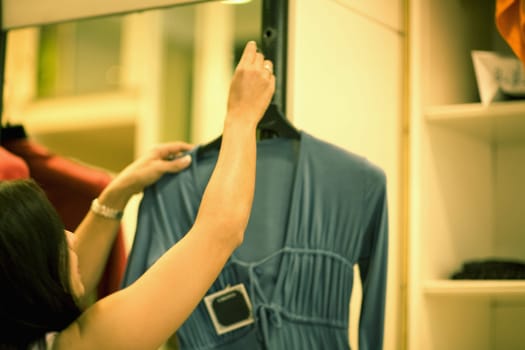 Close-up of a mid adult woman holding a top and standing in a clothing store, Barcelona, Spain