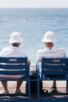 Rear view of a senior couple sitting on chairs on the beach, Barcelona, Spain