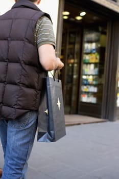 Rear view of a man carrying a shopping bag and walking, Barcelona, Spain