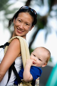 Side profile of a mid adult woman carrying her baby boy