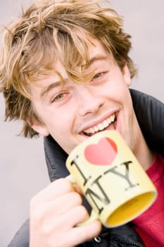 Portrait of a young man holding a coffee cup and smiling