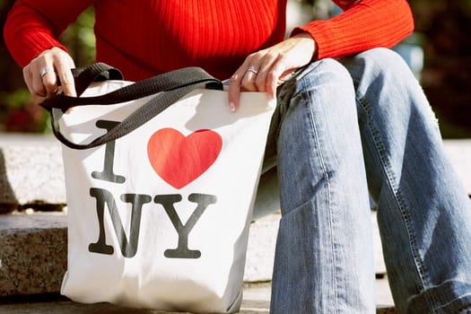 Mid section view of a woman sitting and holding a shopping bag