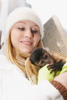 Close-up of a young woman hugging a baby monkey