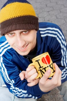 High angle view of a young man holding a mug with I Love New York printed on it
