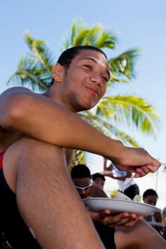 Young man eating at beach party