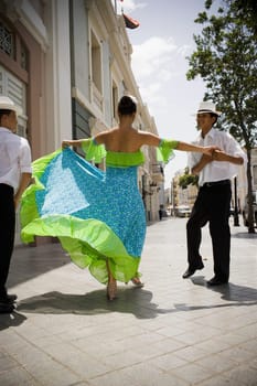 Children in traditional Plena attire dancing in streets of plaza, outdoors