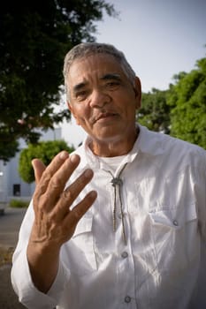 Portrait of senior man gesturing with hands, outdoors