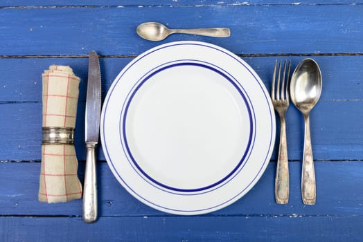plate with silver cutlery on an old blue table