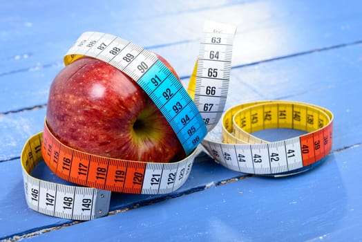 one meter ribbon around apple on the blue table