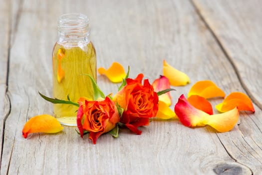 bath oil and orange roses on old wooden background