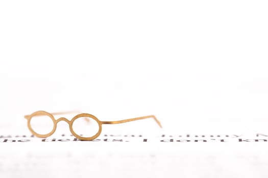 Tiny reading glasses on a white page with black writing and space for text