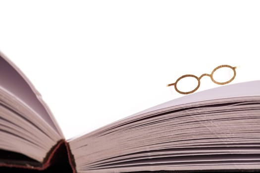 Reading glasses resting on the edge of an open blank book with white pages and space for text