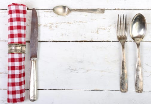 silver cutlery with red towel on an old white table