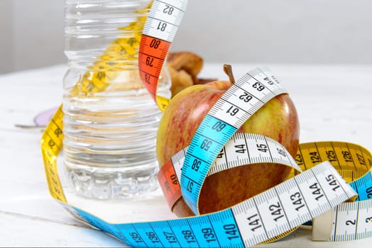 a bottle of water and an apple with  meter ribbon