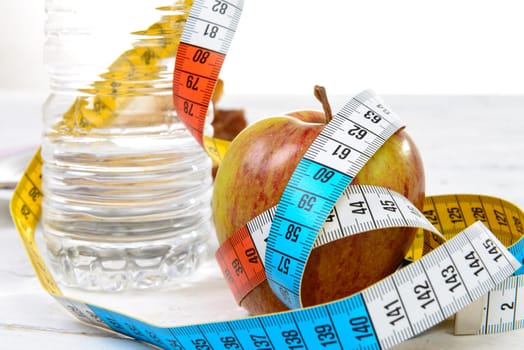 bottle of water and apple with  meter ribbon