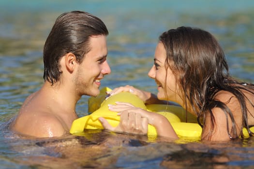 Couple in summer vacation bathing in the water of the beach and looking each other