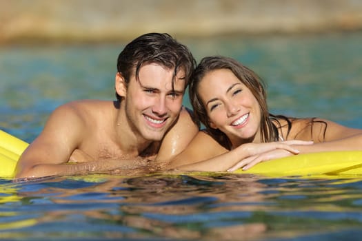 Happy couple bathing on the beach in summer vacation with a perfect white smile and looking at camera