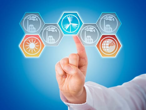 Male index finger activating three renewable energy icons. Hexagonal symbols for solar, wind and geothermal power generation are lighting up. Four smoking factory buttons remain greyed out. Close up.