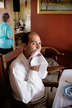 Mature man sitting at the dining table with a mature woman standing in the background