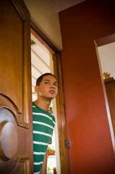 Young man peeking through a door