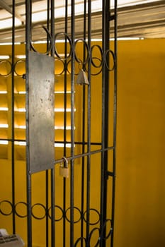 Close-up of a bell and a padlock on a metal grill