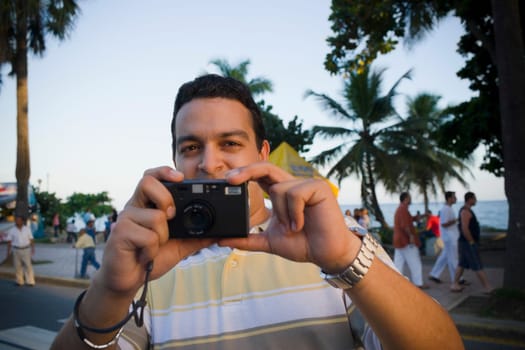 Close-up of a mid adult man holding a camera, Malecon, Santo Domingo, Dominican Republic