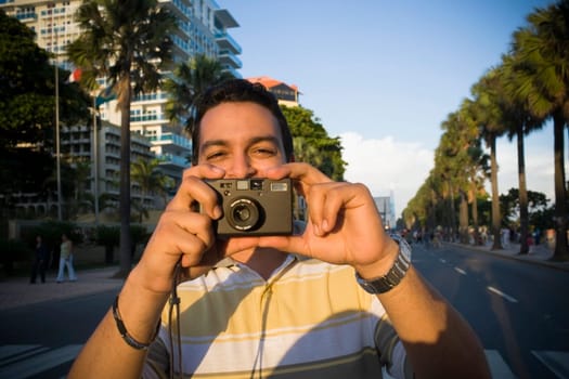 Close-up of a mid adult man holding a camera, Malecon, Santo Domingo, Dominican Republic