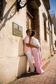 Side profile of a mid adult man embracing a pregnant young woman from behind, Santo Domingo, Dominican Republic