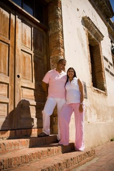 Portrait of a mid adult man with a pregnant young woman standing on steps in front of a door, Santo Domingo, Dominican Republic