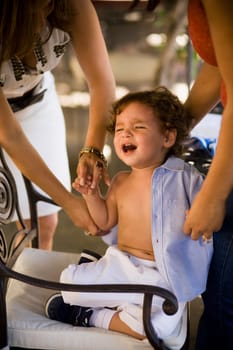 Baby boy crying while his mother dresses him up