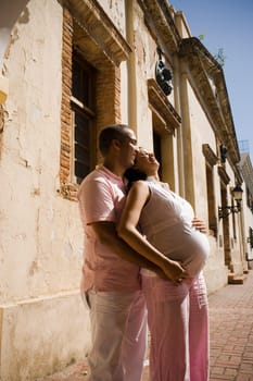 Side profile of a mid adult man embracing a pregnant young woman from behind, Santo Domingo, Dominican Republic